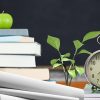 Apple and alarm clock over pile of book in the classroom